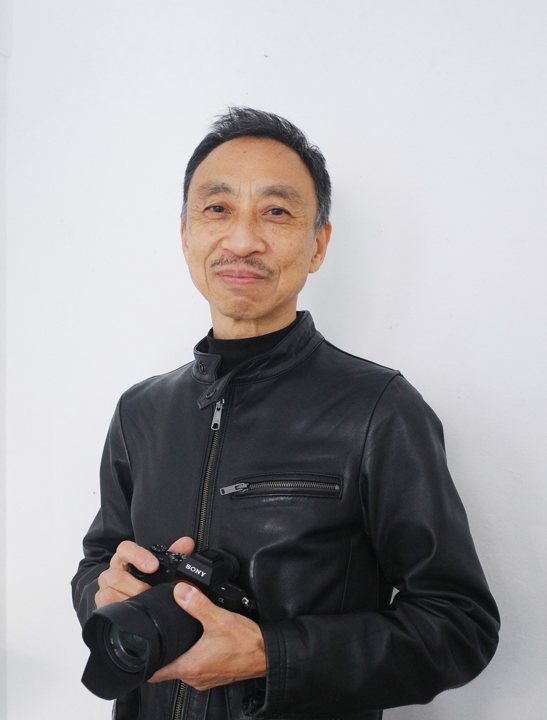 写真家・市川勝弘氏。カメラを手に立つ近影